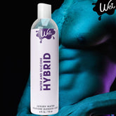 A 4 fl oz (118 ml) bottle of "Wet Hybrid Water + Silicone Blend Based Lubricant" is shown against a person's well-defined, shadowed torso. The bottle displays a white label with purple text, prominently featuring the brand name "Wet" at the top and highlights its hypoallergenic formula.